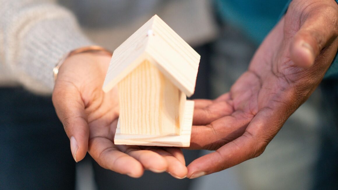 A small wooden miniature house in the palm of a hand